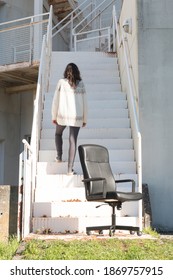 Female Model Climbing Stairs Wearing Home Style Clothes. Woman Working Remotely From Home. Detail Of A Desk Chair.