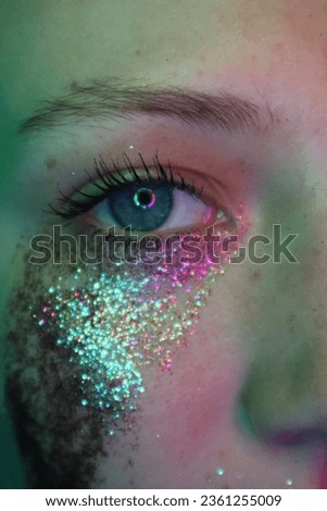 Female model with glitter on her face and hands covering her face