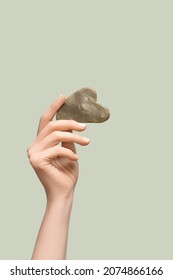 Female Model Hands With Gray Jade Gua Sha Scraper On Gray Background. Spa Body Care Tool. Beauty Care Gua Sha Stone Scraper. Copy Space