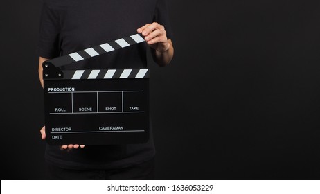 Female model is holding clapperboard or movie slate in studio shooting .It is use in video production and cinema industry on black background.