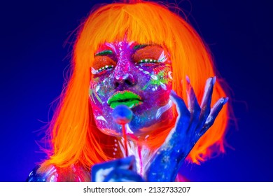 A female model licks sweet candies, a lollipop in neon light, a nightclub disco. Beautiful model girl colorful bright fluorescent makeup - Shutterstock ID 2132733207