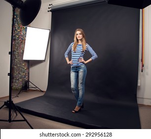 Female model posing at studio in the light flashes. Young beautiful model posing in professionally photo studio. Woman posing during photo shooting in photo studio.