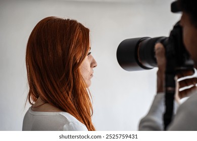 Female model with red hair posing for a professional photographer, captured in a candid and natural moment during a photoshoot. - Powered by Shutterstock