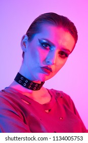 Female model in studio, coloured gel lighting, photography lighting technique. Gels and color. Short hair and chocker, edgy alternative fashio look
