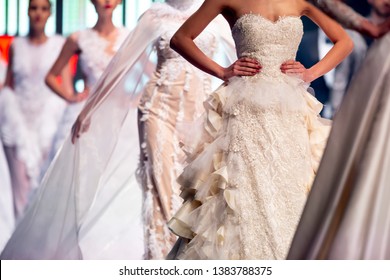 Female Model Walks The Runway In Beautiful White Wedding Dresses During A Fashion Show. Fashion Catwalk Event Showing New Collection Of Clothes. Unrecognizable People.