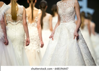 Female models walk the runway in beautiful stylish white wedding dresses during a Fashion Show. Fashion catwalk event showing new collection of clothes.