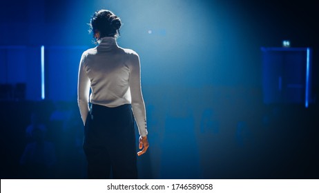 Female Motivational Speaker On Stage, Talking About Happiness, Diversity, Success, Leadership, STEM And How To Be Productive. Woman Presenter Leads Tech Business Conference. Back View Shot