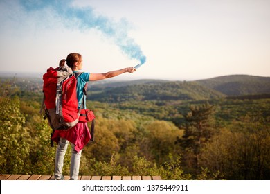 Female Mountaineer Standing On High And Sending Smoke Signal To Hikers Group 