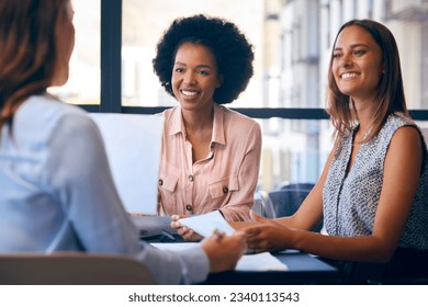 Female Multi-Cultural Business Team Meet Around Boardroom Table With Laptops Discussing Documents - Shutterstock ID 2340113543