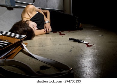 Female Murder Victim Laying On A Dark Alley With A Bloody Knife.  The Crime Scene Is A Dark
Street Alley. 