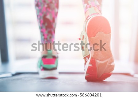 Female muscular feet in sneakers running on the treadmill at the gym