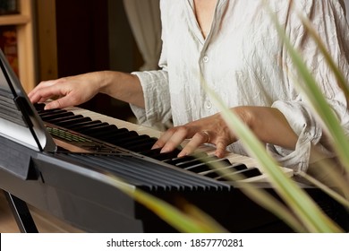 Female musician playing the digital piano or electronic keyboard at home. Music Education and Entertainment. Online music lessons.