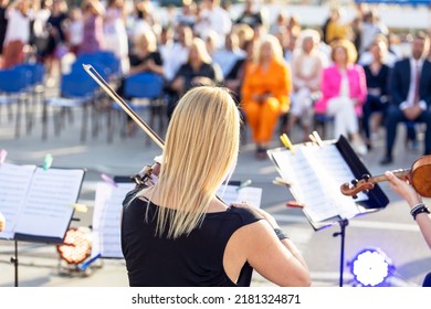 Female Musician Playing Violin At Classical Music Concert Outdoors In Front Of Blurred Audience