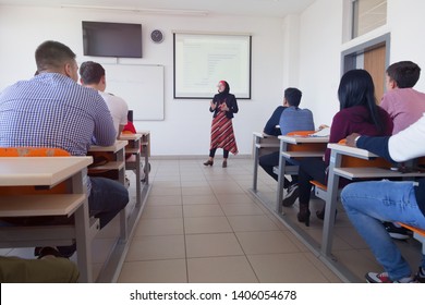 Female muslim professor explain lesson to students and interact with them in the classroom.Helping a students during class. University student being helped by female lecturer during class. - Shutterstock ID 1406054678