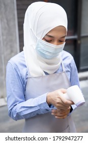 Female Muslim Retail Business Staff Or Grocery Shop Keeper Checking Scanned Fever Temperature From Portable Thermal Scan Device