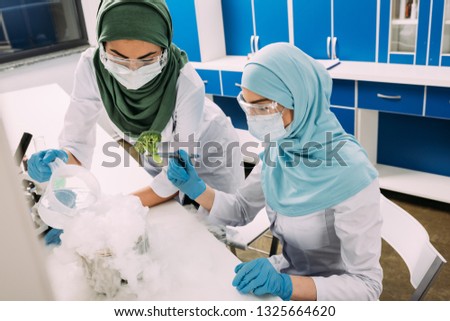 female muslim scientists experimenting with dry ice and broccoli in chemical laboratory