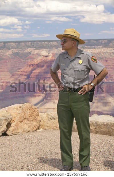 Female National Park ranger\
looking at South Rim of Grand Canyon National Park in mid-summer in\
Arizona