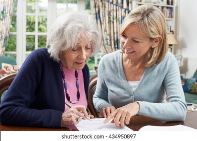 Female Neighbor Helping Senior Woman To Complete Form