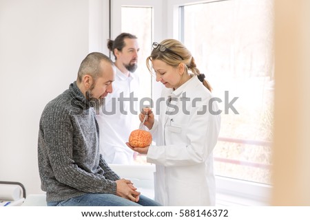 female neurologist is showing a male patient something on a synthetic brain