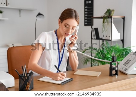 Female notary public talking by phone while working in office