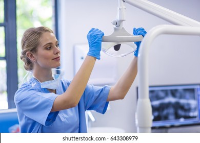 Female nurse adjusting dental light in clinic - Powered by Shutterstock