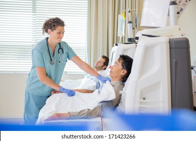 Female Nurse Assisting Patient Undergoing Renal Dialysis In Hospital Room