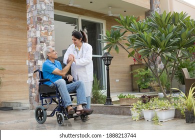 Female Nurse Assisting A Senior Man In A Wheelchair