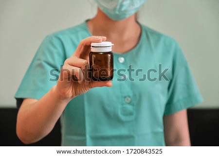 A female nurse with a brown medicine bottle in her hand