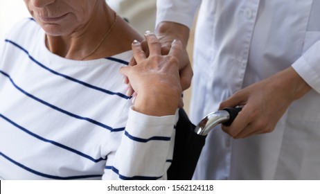 Female nurse carer paramedic support disabled senior adult grandma patient sit on wheelchair put hand on shoulder help old paralyzed lady, elder disability handicap assistance concept, close up view - Powered by Shutterstock