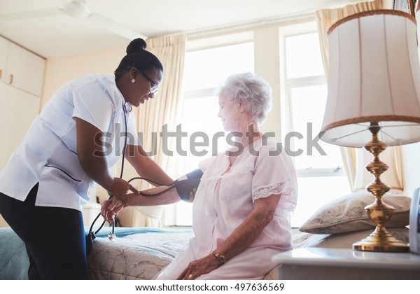 Female nurse doing blood pressure measurement of a\
senior woman patient. Doctor checking blood pressure of an elderly\
woman at old age home.