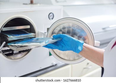 Female Nurse Doing Sterilization Of Dental Medical Instruments In Autoclave. Sterilization Department At Dental Clinic