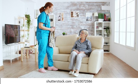 Female Nurse Helping Senior Woman Getting Dressed In Nursing Home