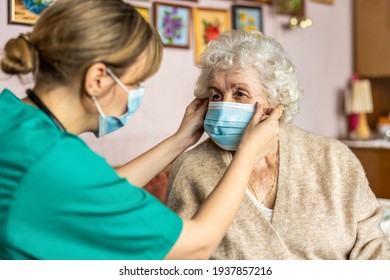 Female Nurse Helping A Senior Woman To Put On Protective Face Mask During Home Visit
