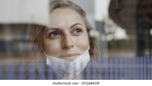 Female Nurse In Hospital Removing Protective Face Mask Looking Trough Window With Positive Emotion During Lockdown Covid19 Pandemic