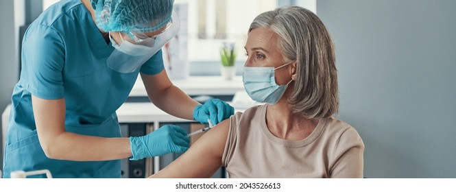 Female Nurse Making Injection To Mature Woman While Working In The Hospital