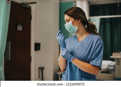 Female Nurse With A Mask Putting On Gloves