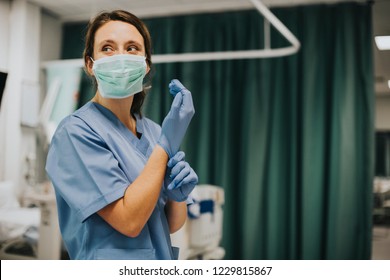Female nurse with a mask putting on gloves