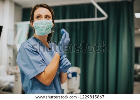 Female nurse with a mask putting on gloves 商業照片 © 