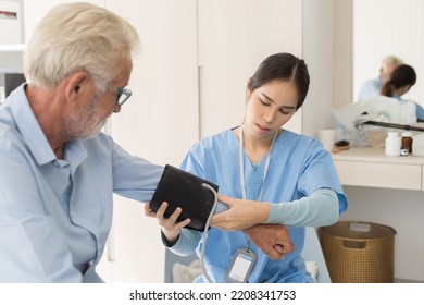 Female Nurse Measure The Pressure Senior Man At Hospital Ward. Asian Female Nurse Caring Elderly Man Patient In Room At Nursing Home. Hospital Care And Older Adults Concept