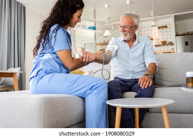 Female Nurse Measures Blood Pressure To Senior Man While Being In A Home Visit.