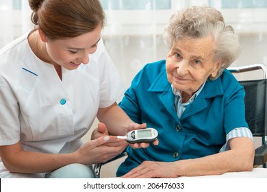 Weibliche Krankenschwester, die den Blutzuckerspiegel von älteren Frauen misst