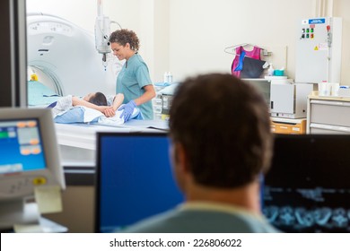 Female Nurse Preparing Patient For CT Scan Test In Lab