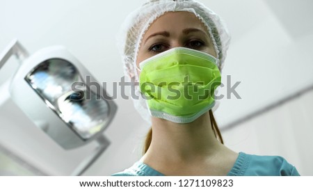 Female nurse in preparing for surgery in clinic, looking at patient, medicine