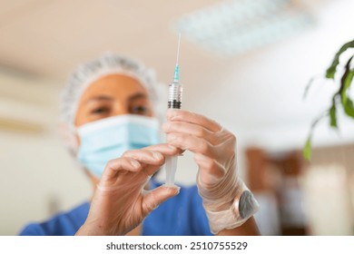 Female nurse in protective face mask prepared a syringe for injection, filling it with medicine - Powered by Shutterstock