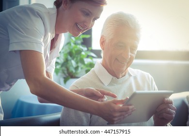 Female Nurse Showing Medical Report To Senior Man On Digital Tablet At Home
