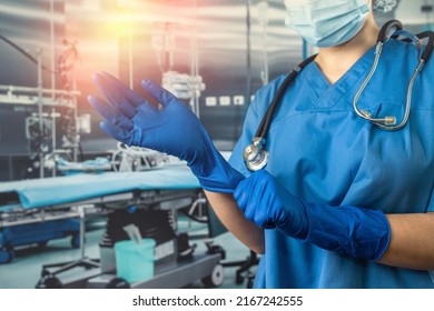 Female nurse wear blue uniform with a mask putting on rubber latex blue gloves  to complicated surgical operation