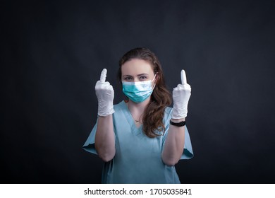 Female  Nurse  Wearing A Turquoise Surgical Mask From Coronavirus, Double Rude Gesture, Dark Background