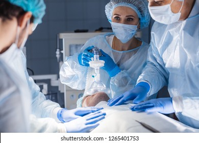 Female Nurses Putting Oxygen Mask On Patient In Operation Room. Pre Oxygenation For General Anesthesia. Surgery Equipment