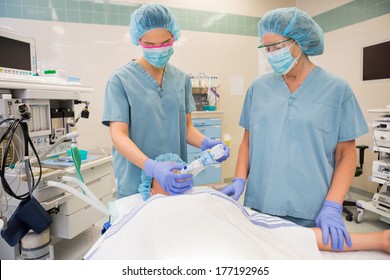 Female nurses putting oxygen mask on patient in operation room - Powered by Shutterstock