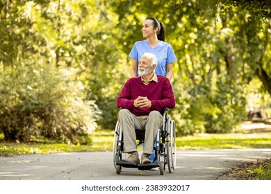 Female nursing assistant and elderly man in wheelchair enjoying autumn in the park. - Powered by Shutterstock